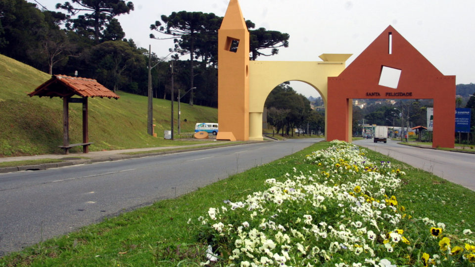 Fachada de residência contemporânea em Curitiba com linhas retas, grandes aberturas em vidro e integração com vegetação nativa, cores neutras com toques de #4a3aad.