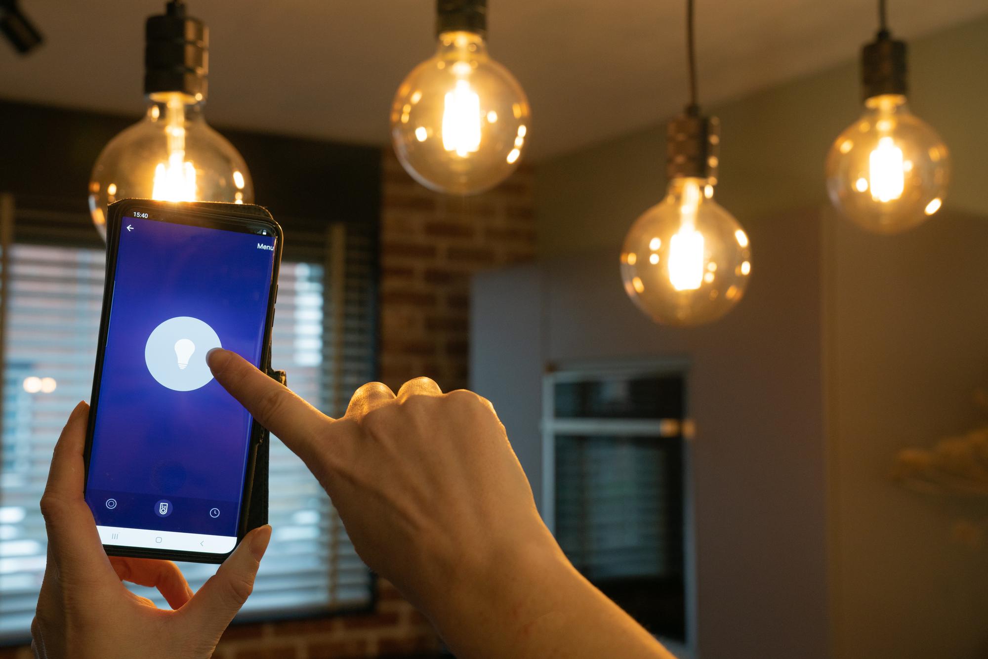 Área gourmet externa integrada ao jardim com iluminação automatizada cênica em tons violeta e azul suave