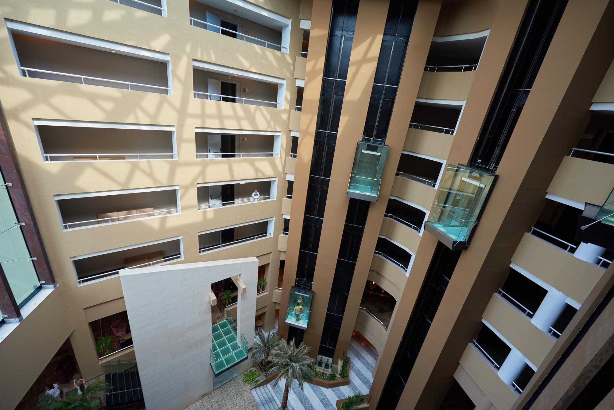 Fachada de edifício residencial de alto padrão em Curitiba com integração de jardins verticais e design contemporâneo em tons de cinza e madeira.