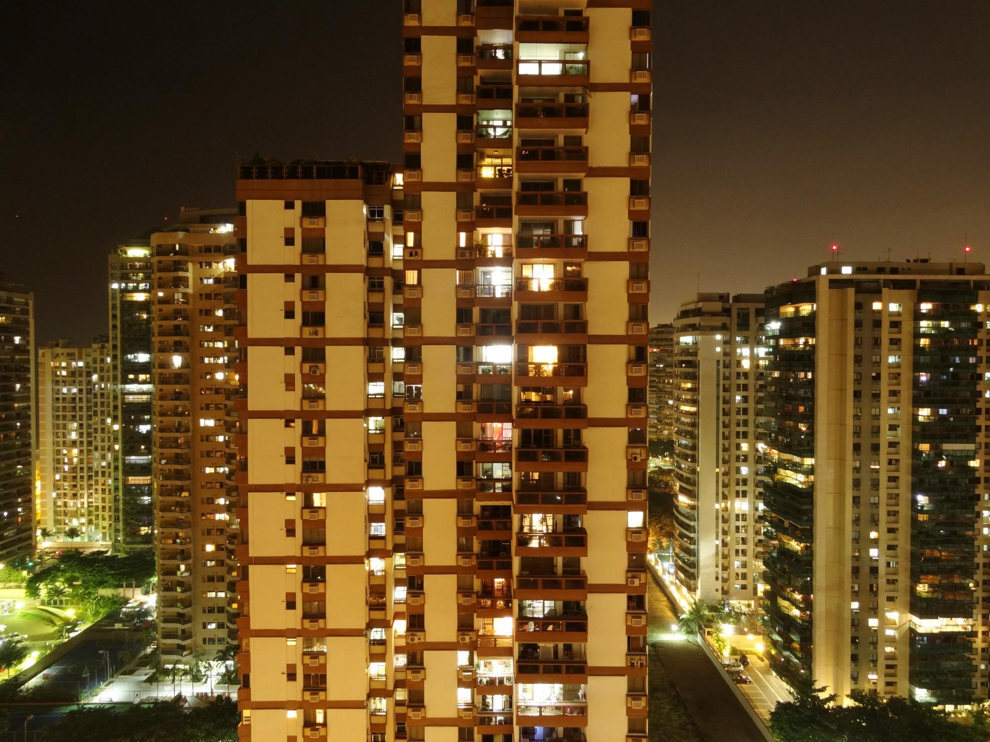 Interior de sala de estar luxuosa com automação residencial, iluminação cênica em tons quentes e integração com varanda gourmet.