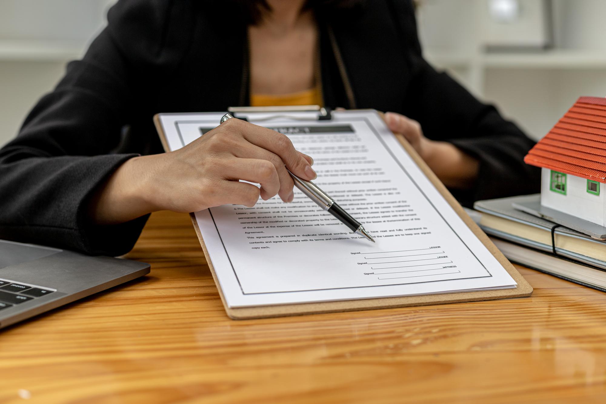 O vendedor de imóveis aponta para a caixa de sinalização do contrato de compra, o cliente concorda em assinar a venda após ouvir e ler os detalhes do contrato. Ideias de negociação imobiliária.
