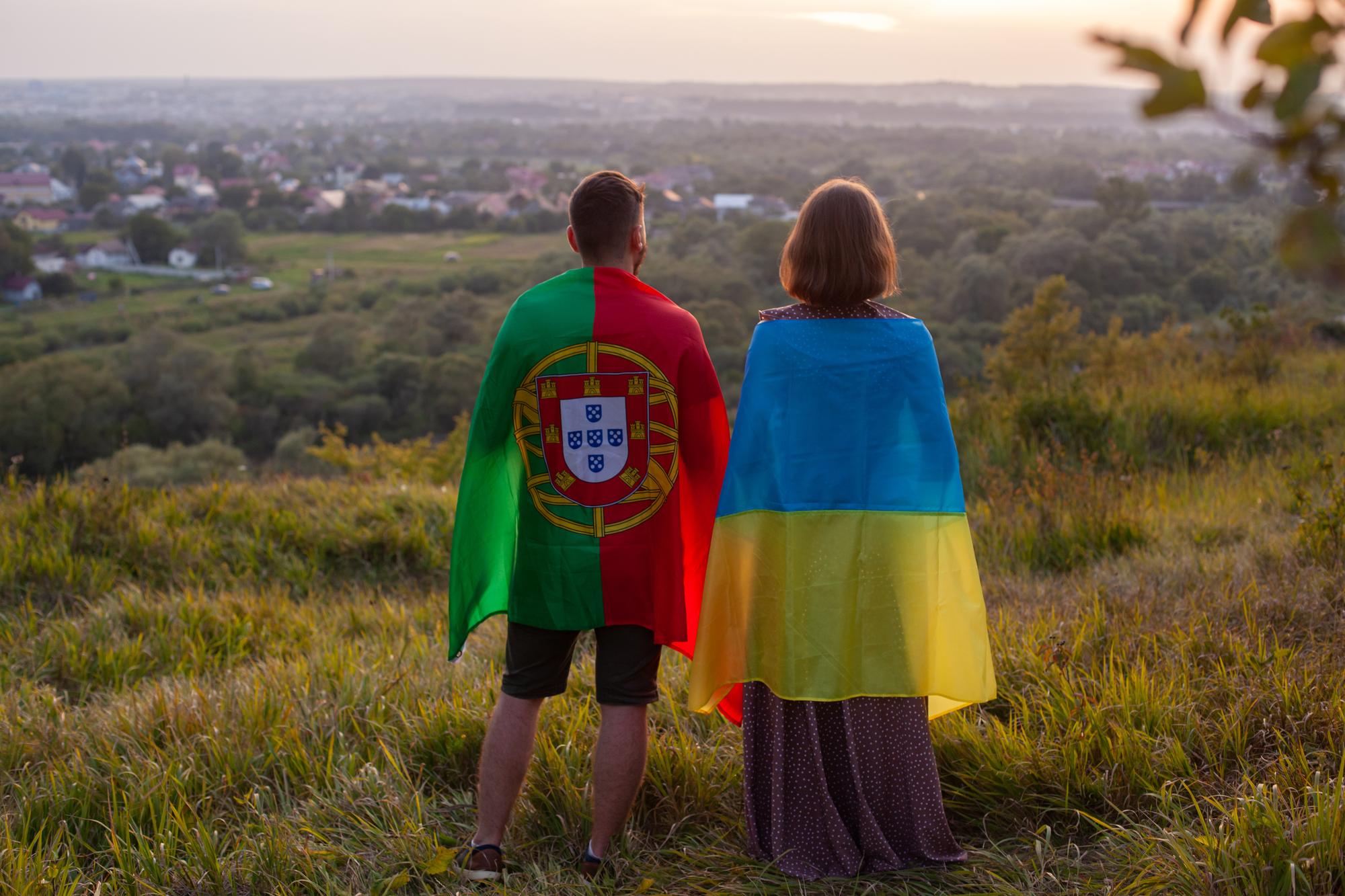Casal coberto de bandeiras da Ucrânia e Portugal