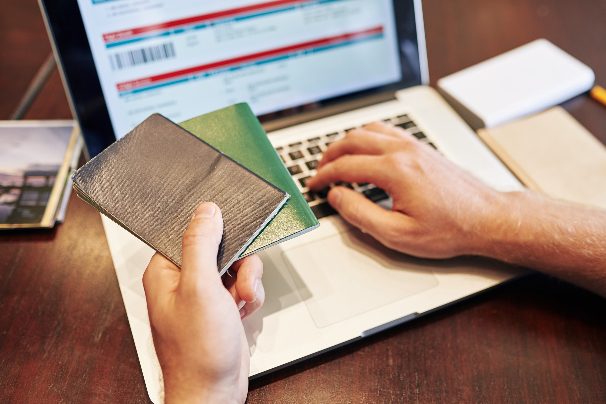 Imagem de close-up de um homem digitando as informações do passaporte ao comprar passagens aéreas online