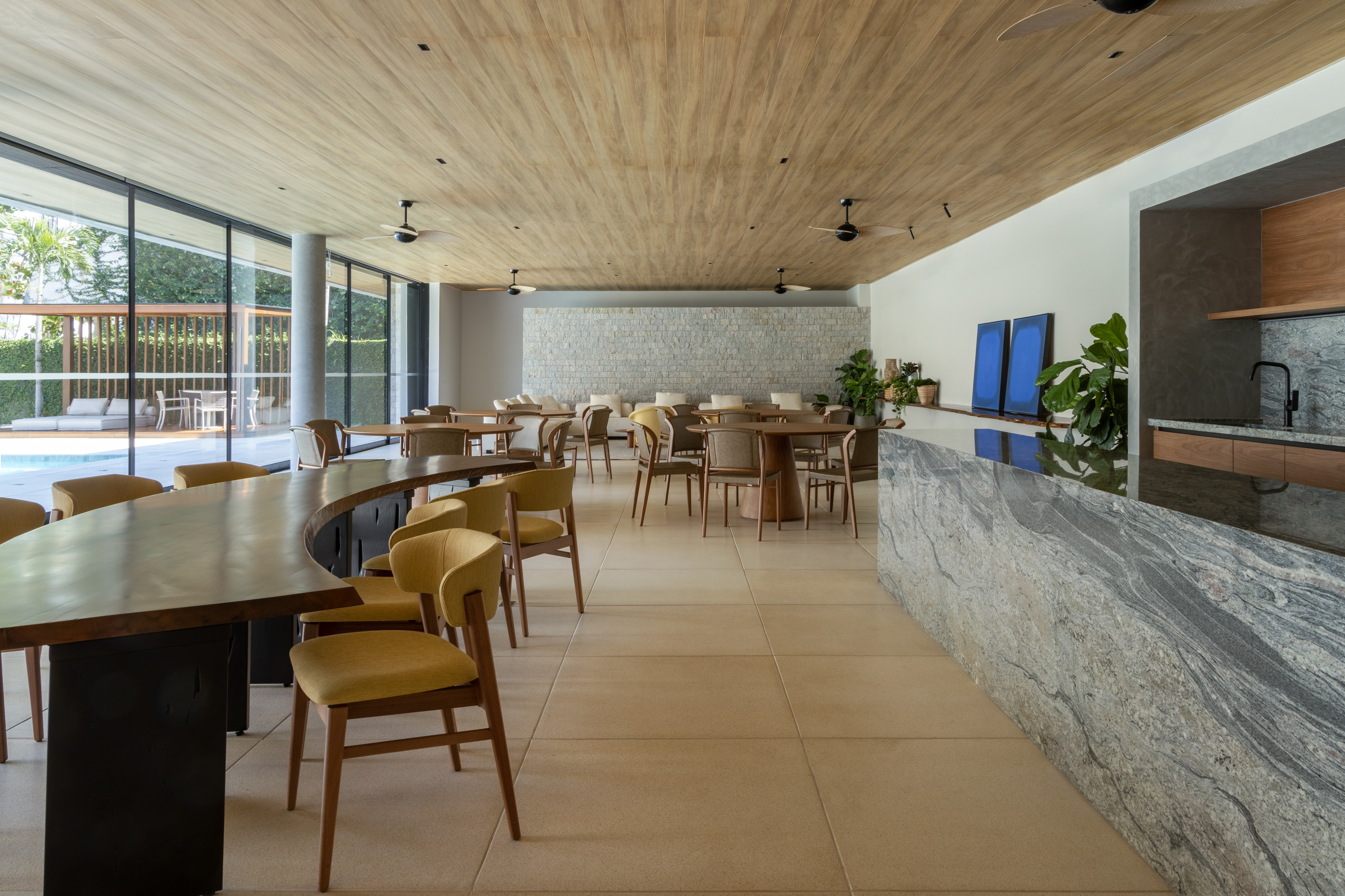 Mesa de jantar em madeira maciça com bordas orgânicas em uma área gourmet luxuosa e integrada